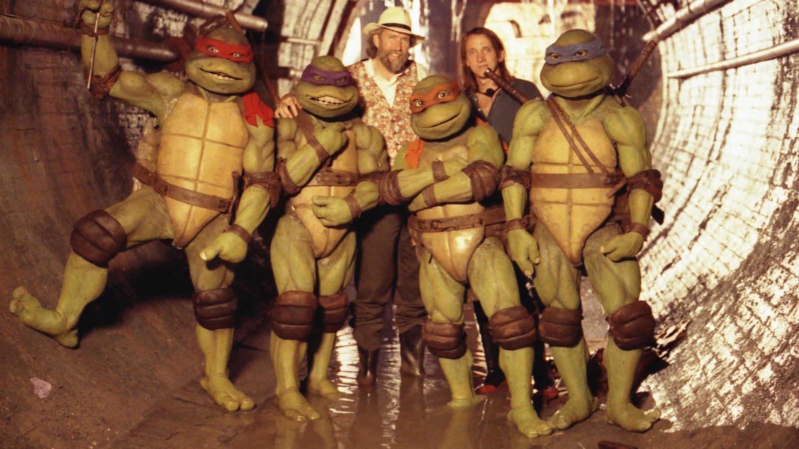 Jim Henson and director Steve Barron with the four Teenage Mutant Ninja Turtles in their Creature Shop suits, on the sewer set